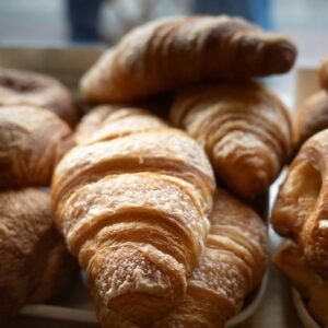Fresh croissants in a bakery, perfect example of French pastry. Captured indoors under soft lighting.