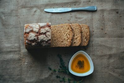 Sliced bread with olive oil on burlap, ideal for culinary themes.