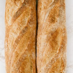 Freshly baked baguettes on a marble surface, showcasing rustic texture and golden crust.