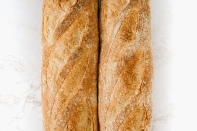 Freshly baked baguettes on a marble surface, showcasing rustic texture and golden crust.