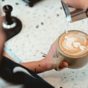 Barista crafting intricate latte art in a cozy cafe setting, showcasing skill and precision.