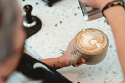 Barista crafting intricate latte art in a cozy cafe setting, showcasing skill and precision.